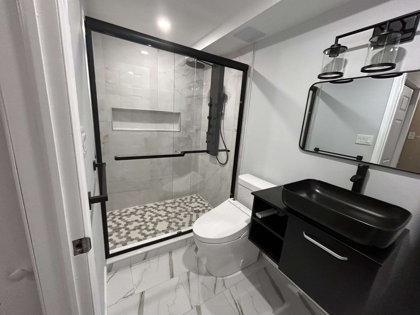 White kitchen renovation with black appliances and wood flooring